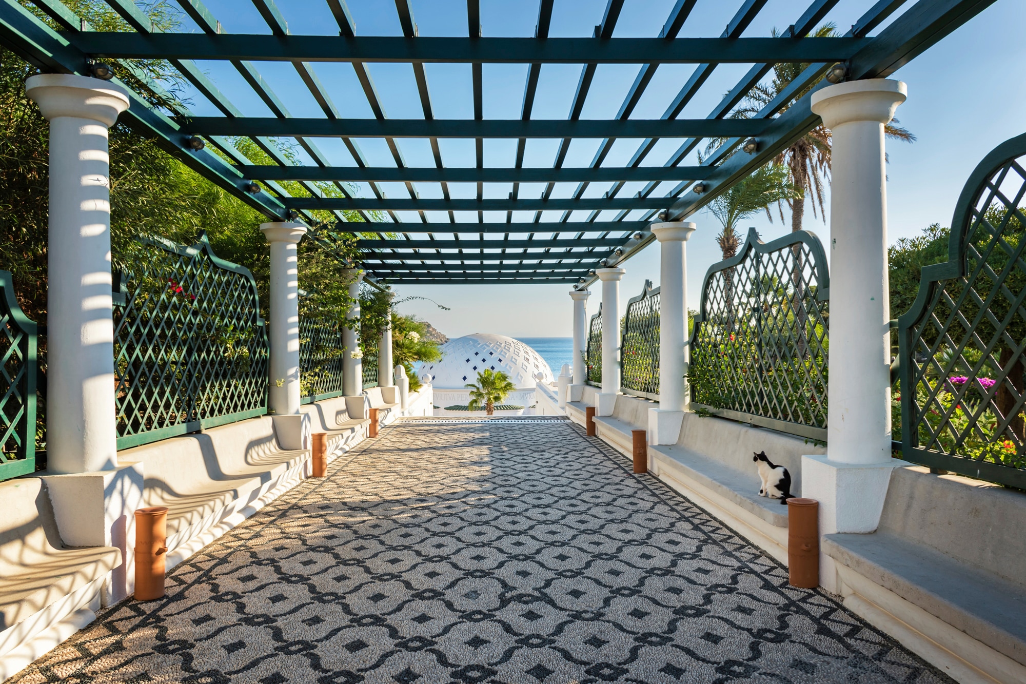 Papermoon Fototapete »PERGOLA-RHODOS BLUMEN SEE MEER TERRASSE PALMEN DÜNEN« günstig online kaufen