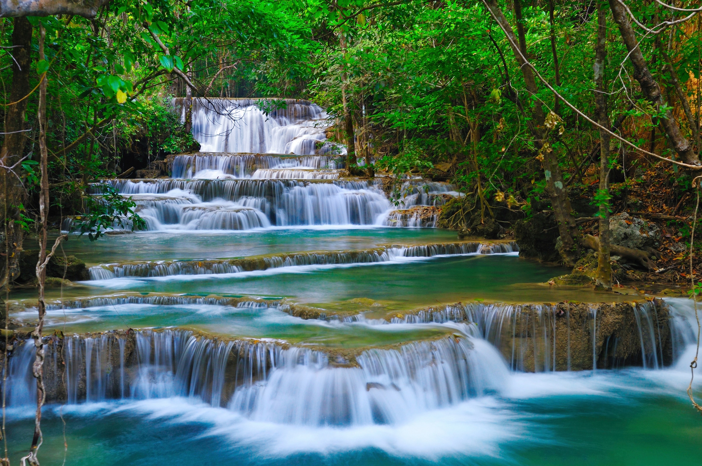 Papermoon Fototapete »WASSERFALL-BÄUME FLUSS SEE STEINE BLUMEN BERGE SONNE« günstig online kaufen